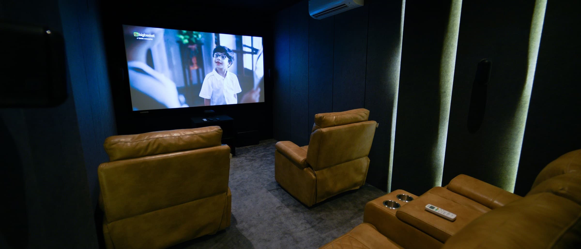 Small dedicated home theater with tan recliners and acoustic wall panels