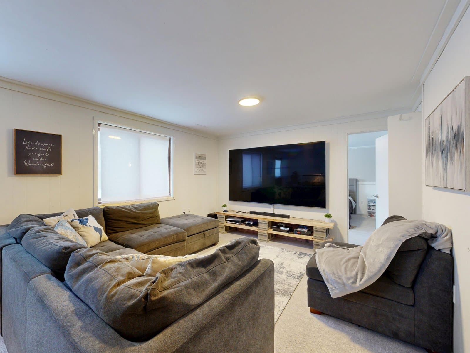 Bright den with a sectional sofa facing a wall-mounted TV